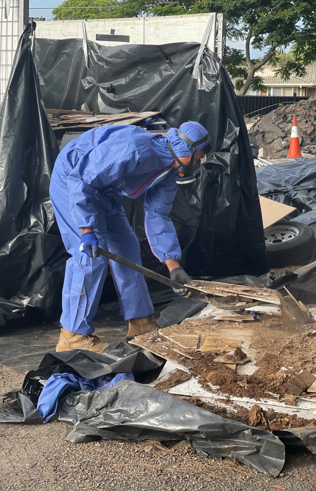 Worker in coveralls and a respirator removing asbestos material the right way